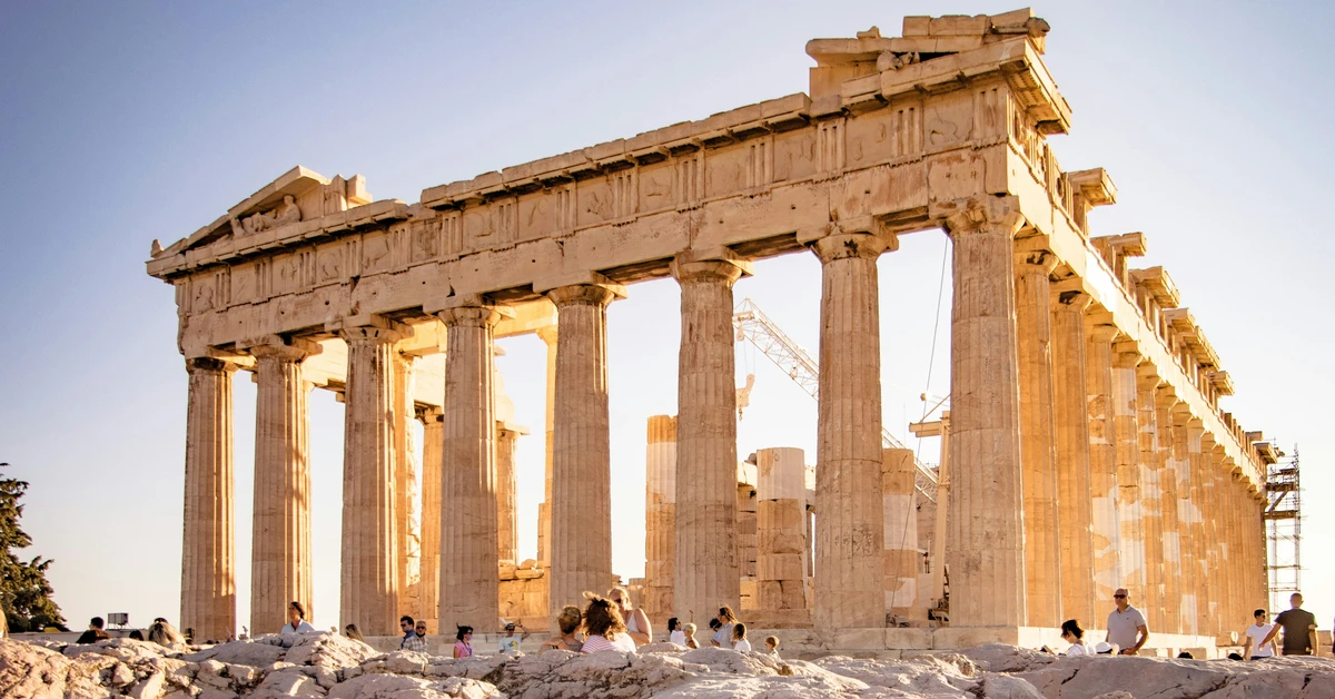 Tourists admiring the marble columns of the Parthenon in warm sunlight