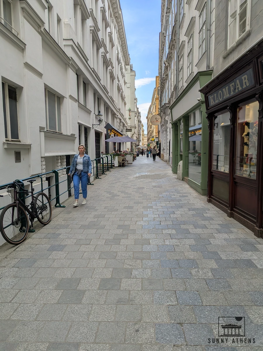 Walking along a historic cobblestone street lined with traditional facades and cafes in central Vienna
