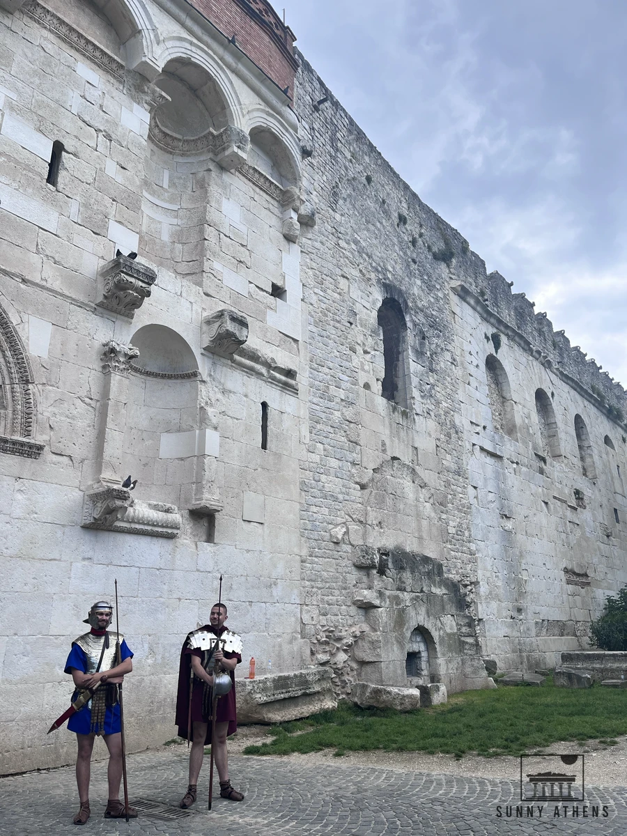Historical reenactors dressed as Roman soldiers standing outside the ancient stone walls near the Golden Gate in Split