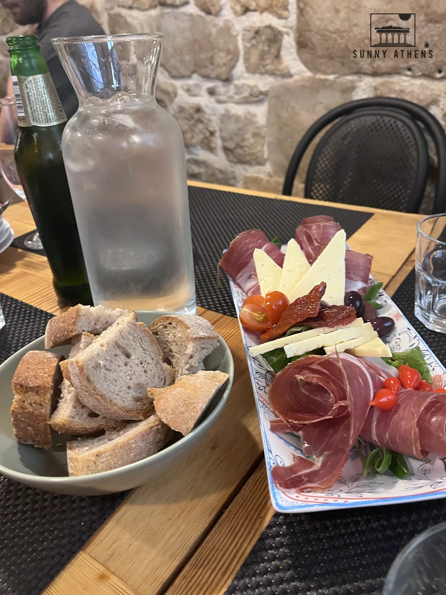 Platter of sliced Dalmatian prosciutto, local cheeses, olives, and bread on a wooden dining table at Villa Spiza