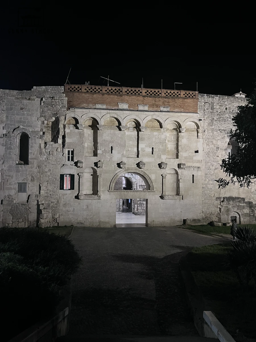 Illuminated Roman stone facade and arched entrance of the Golden Gate at night in Split
