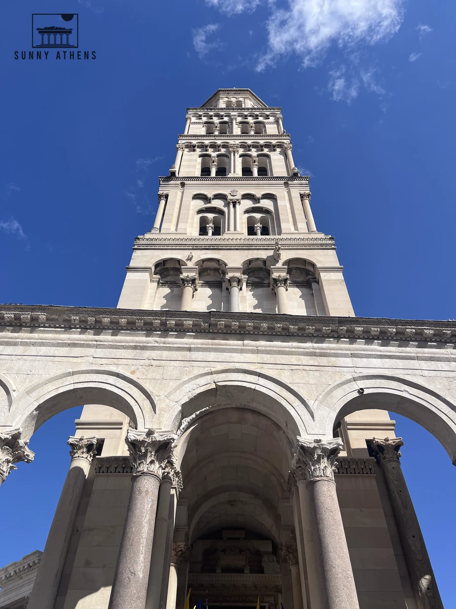 Looking up through Roman stone arches at the towering bell tower of Saint Domnius Cathedral against a clear sky