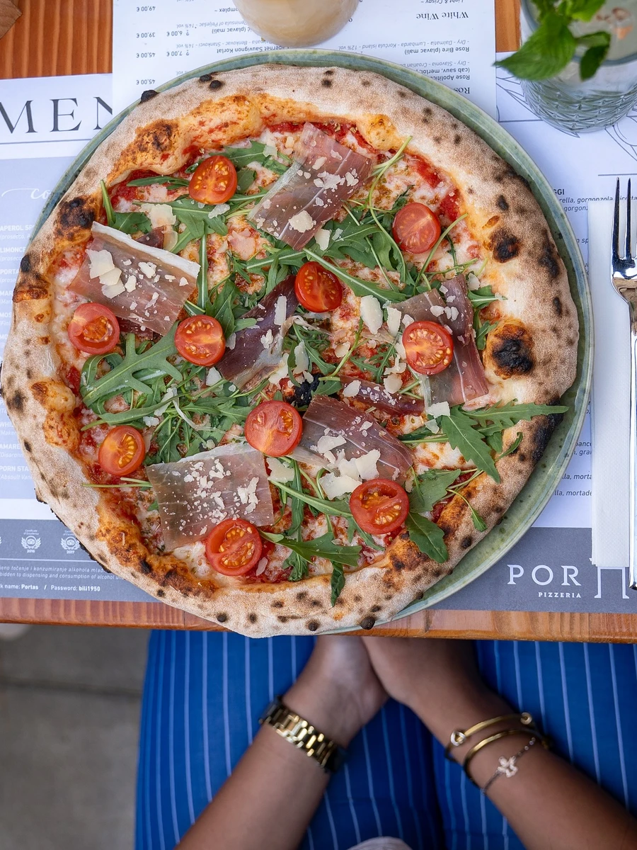 Stone-baked pizza topped with prosciutto, rocket, and cherry tomatoes at Pizzeria Portas