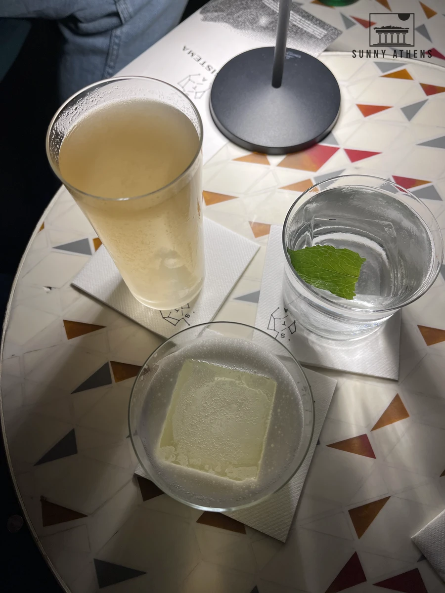 Three craft cocktails served with clear ice and fresh mint on a graphic mosaic table at Bar Sistema