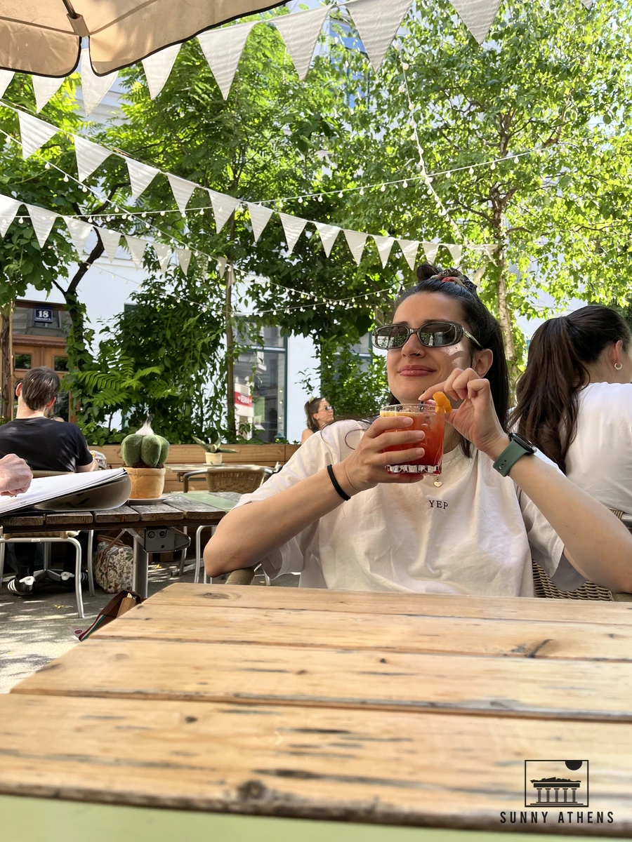 Chrysavgi enjoying a drink at an outdoor table outside die freunderlwirtschaft in Vienna's Servitenviertel