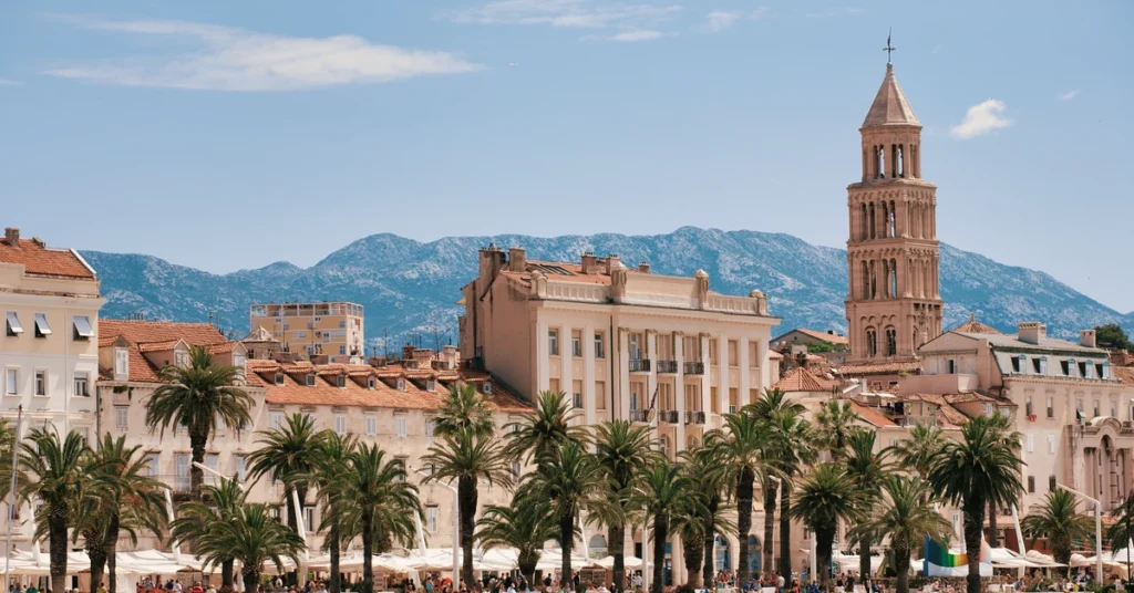 View from the water looking toward the palm-lined Riva promenade, historic facades, and Saint Domnius bell tower in Split