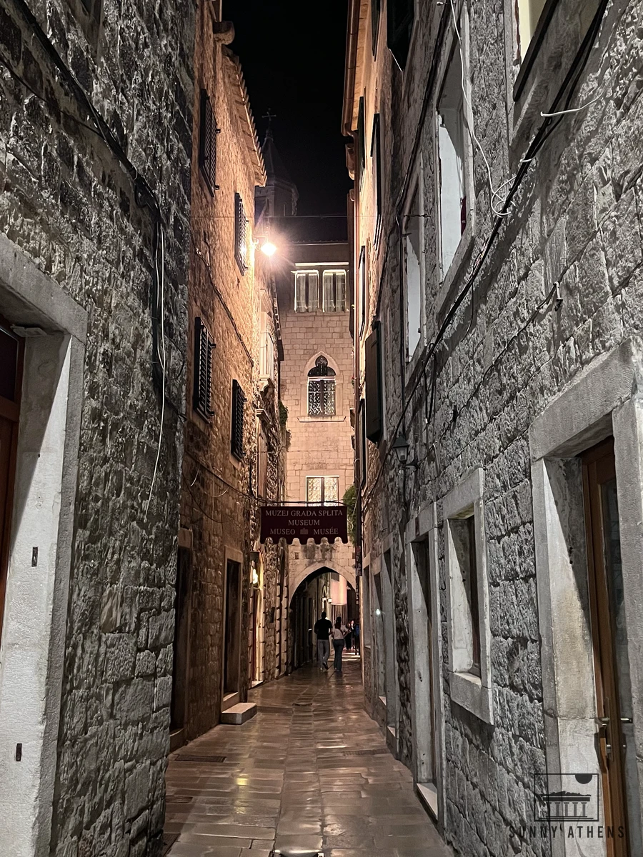 Narrow stone alley in Split Old Town illuminated at night leading toward the city museum archway